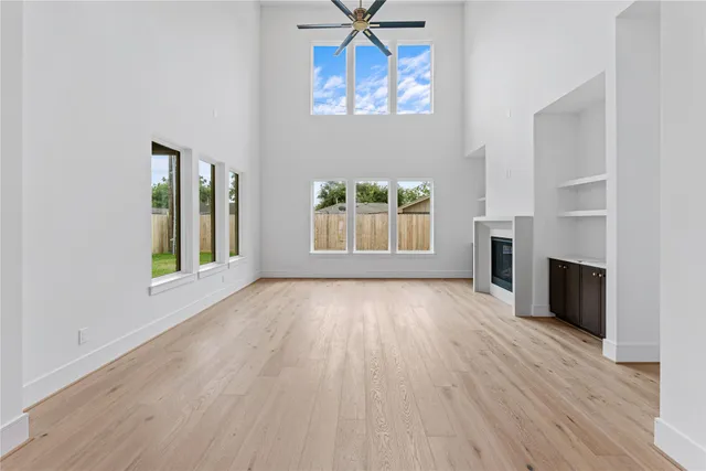 an empty room with windows fireplace and wooden floor