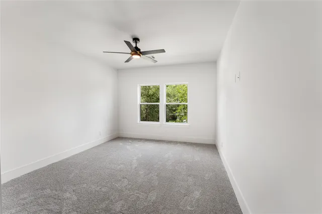 an empty room with a window and a ceiling fan