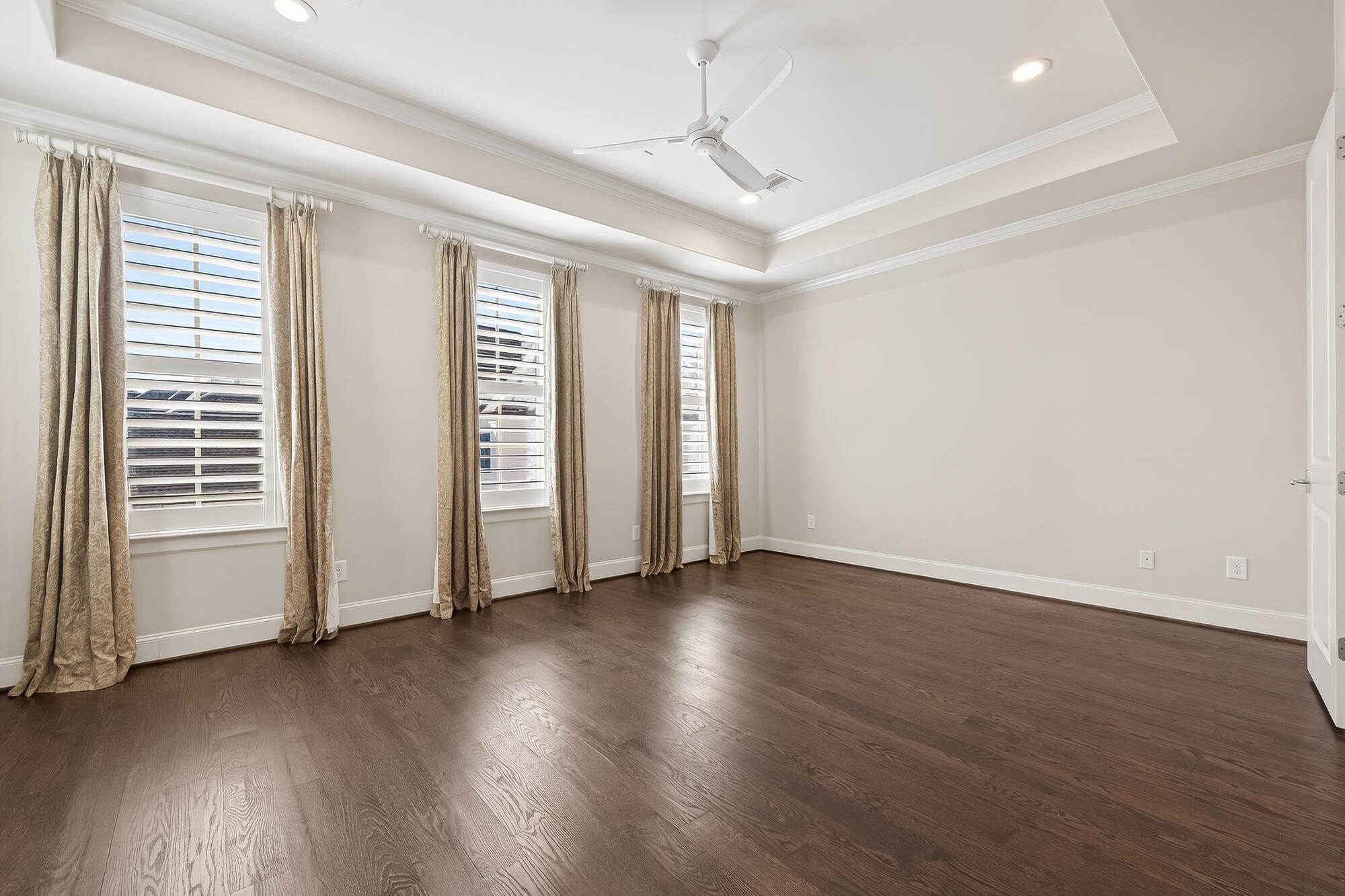 122 Gateway Park Place Spring, TX 77380 - Photo 28 of 44 Light-filled bedroom with tray ceiling, ceiling fan, upgraded wood floors, and walls of windows.