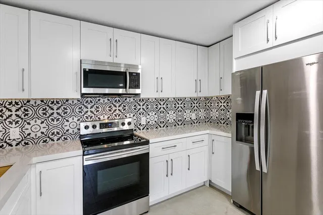 a kitchen with white cabinets and stainless steel appliances