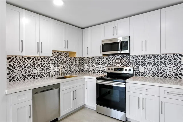 a kitchen with white cabinets and appliances