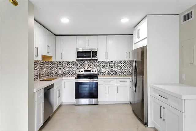 a kitchen with stainless steel appliances granite countertop a refrigerator stove a sink and dishwasher with wooden cabinet