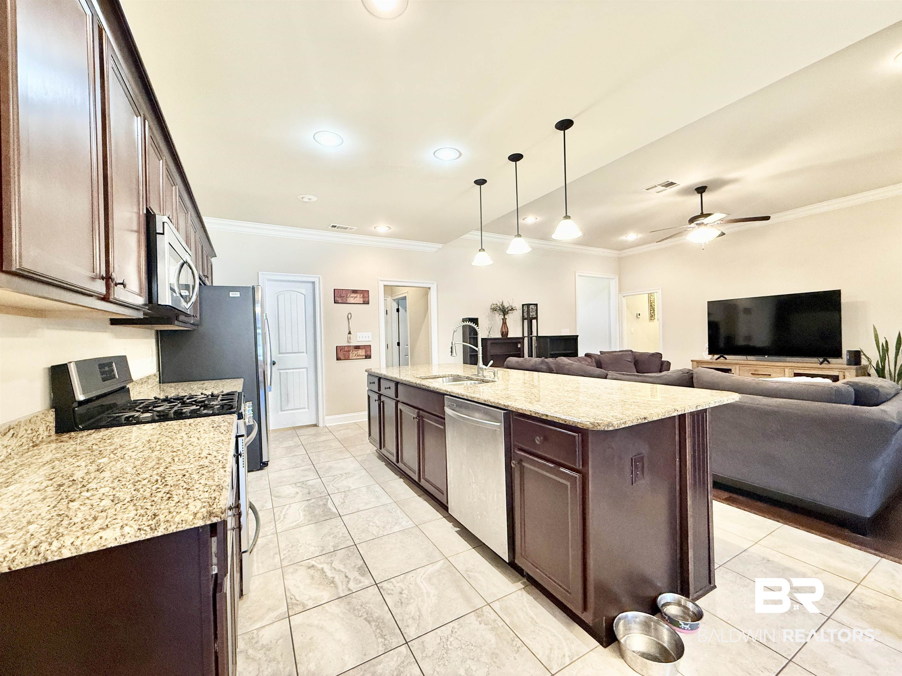 7011 Rocky Rd Loop Gulf Shores, AL 36542 - Photo 66 of 66 Kitchen with appliances with stainless steel finishes, crown molding, open floor plan, a center island with sink, and decorative light fixtures