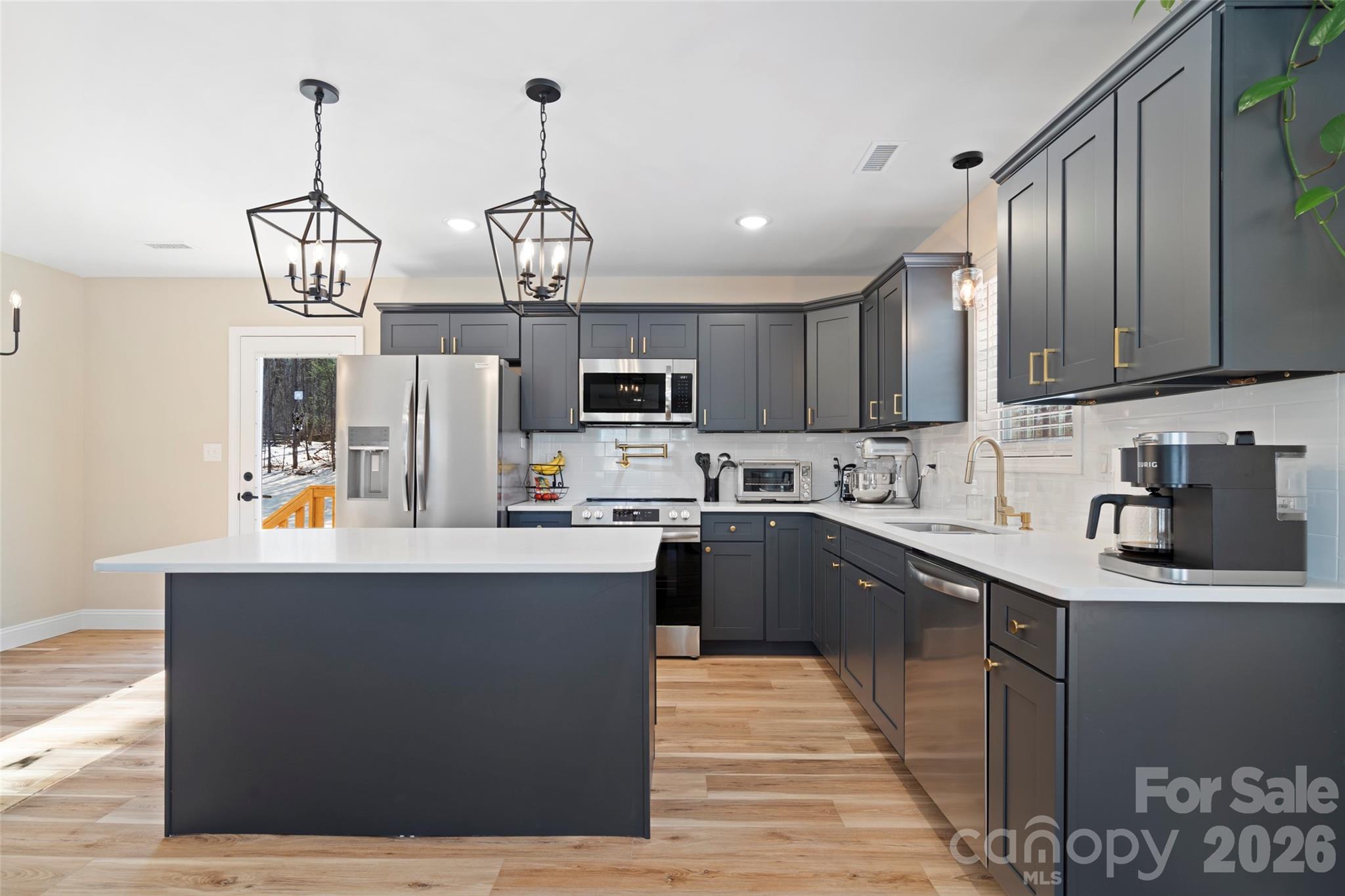 5961 Charlie Little Road Granite Falls, NC 28630 - Photo 3 of 29 a kitchen with stainless steel appliances granite countertop a sink dishwasher a stove top oven a dining table and chairs with wooden floor