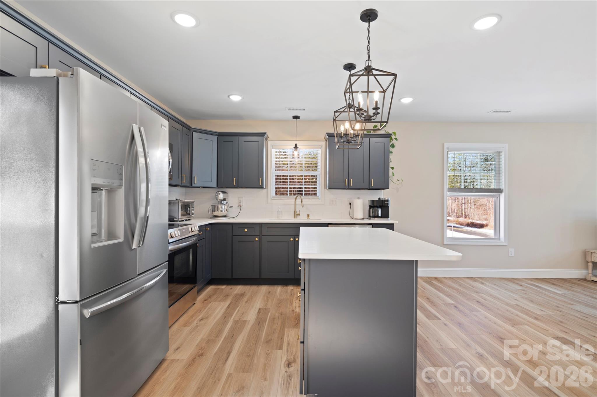 5961 Charlie Little Road Granite Falls, NC 28630 - Photo 4 of 29 a kitchen with stainless steel appliances granite countertop a refrigerator a sink dishwasher a stove and white cabinets with wooden floor