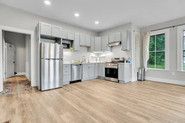 a kitchen with stainless steel appliances kitchen island granite countertop a refrigerator oven a sink and dishwasher with wooden floor