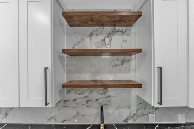 a kitchen with granite countertop white cabinets a stove a sink and dishwasher with wooden floor