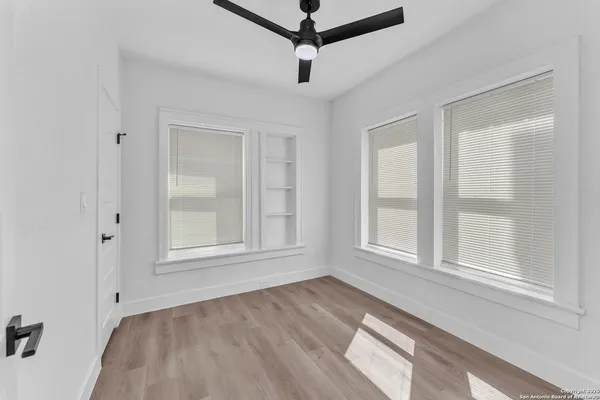 a view of empty room with wooden floor and fan