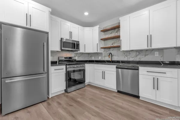 a kitchen with granite countertop a refrigerator stove top oven and sink