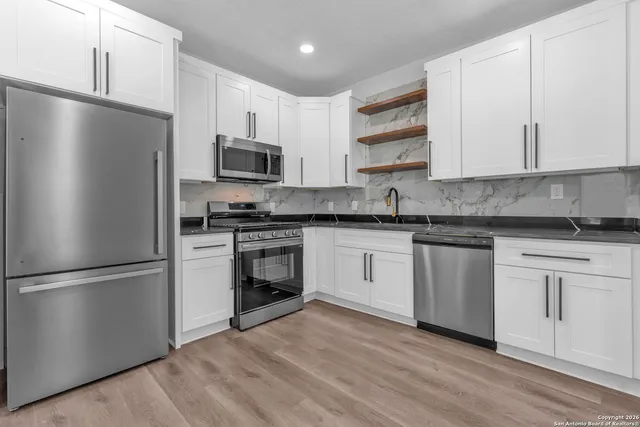 a kitchen with granite countertop a refrigerator stove top oven and sink