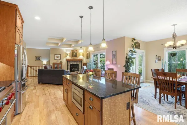 a open kitchen with stainless steel appliances granite countertop a stove top oven a dining table and chairs with wooden floor