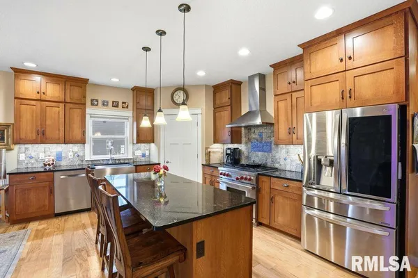 a kitchen with stainless steel appliances granite countertop a sink a stove and refrigerator