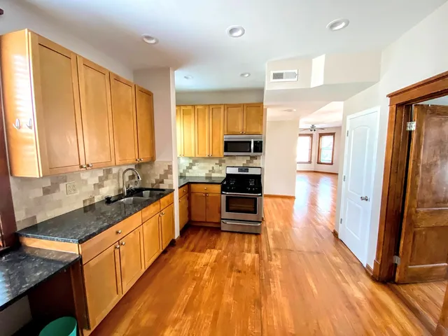 a large kitchen with stainless steel appliances granite countertop a large stove a sink dishwasher and a refrigerator with wooden floor