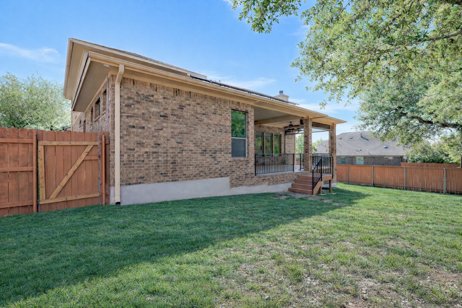 1020 Winding Way Drive Georgetown, TX 78628 - Photo 29 of 32 The property features a brick exterior, a covered patio with a ceiling fan, and a spacious green lawn