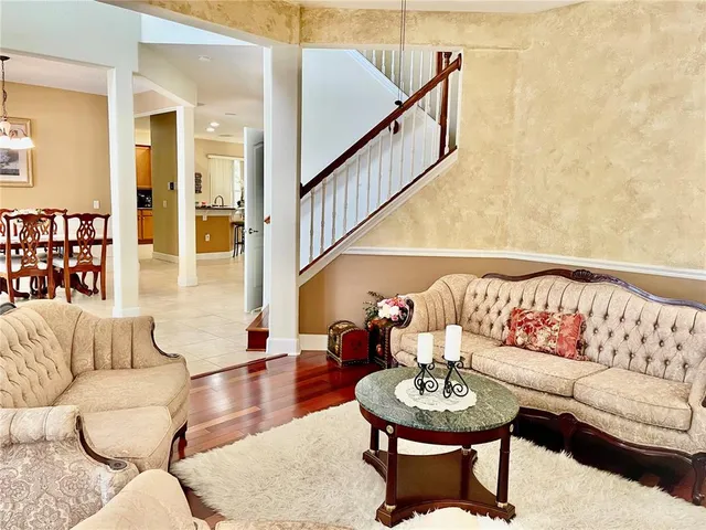 a living room with furniture and a dining table with wooden floor