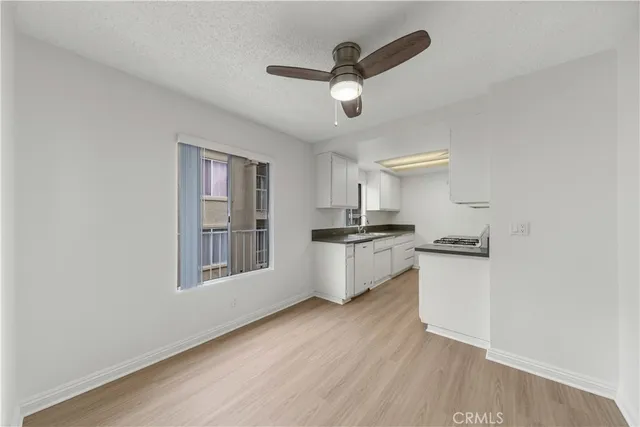 a kitchen with cabinets wooden floor and a ceiling fan
