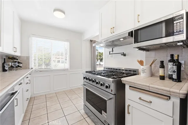 a kitchen with stainless steel appliances granite countertop a sink a stove a microwave and wooden cabinets