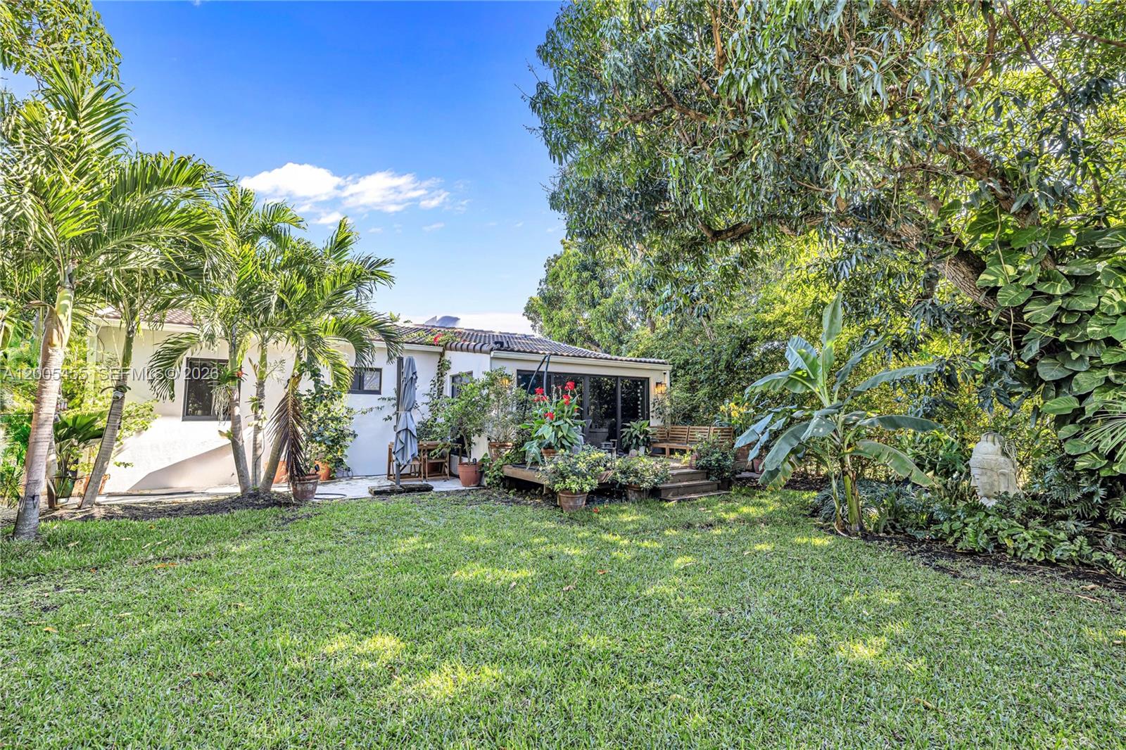 3030 Southwest 2nd Avenue Miami, FL 33129 - Photo 15 of 15 a view of a backyard with table and chairs potted plants and a large tree