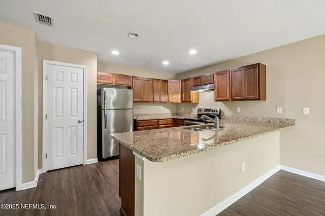 a kitchen with stainless steel appliances granite countertop a sink refrigerator and cabinets