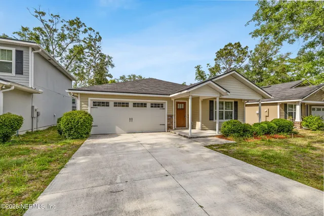 a front view of a house with a yard and potted plants