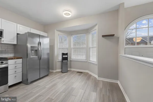 a kitchen with white cabinets and wooden floor
