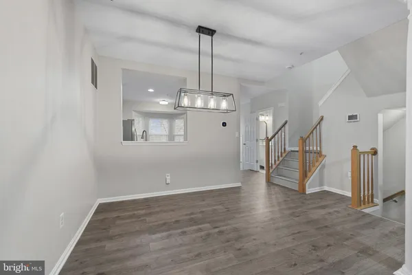 an empty room with wooden floor chandelier and entryway