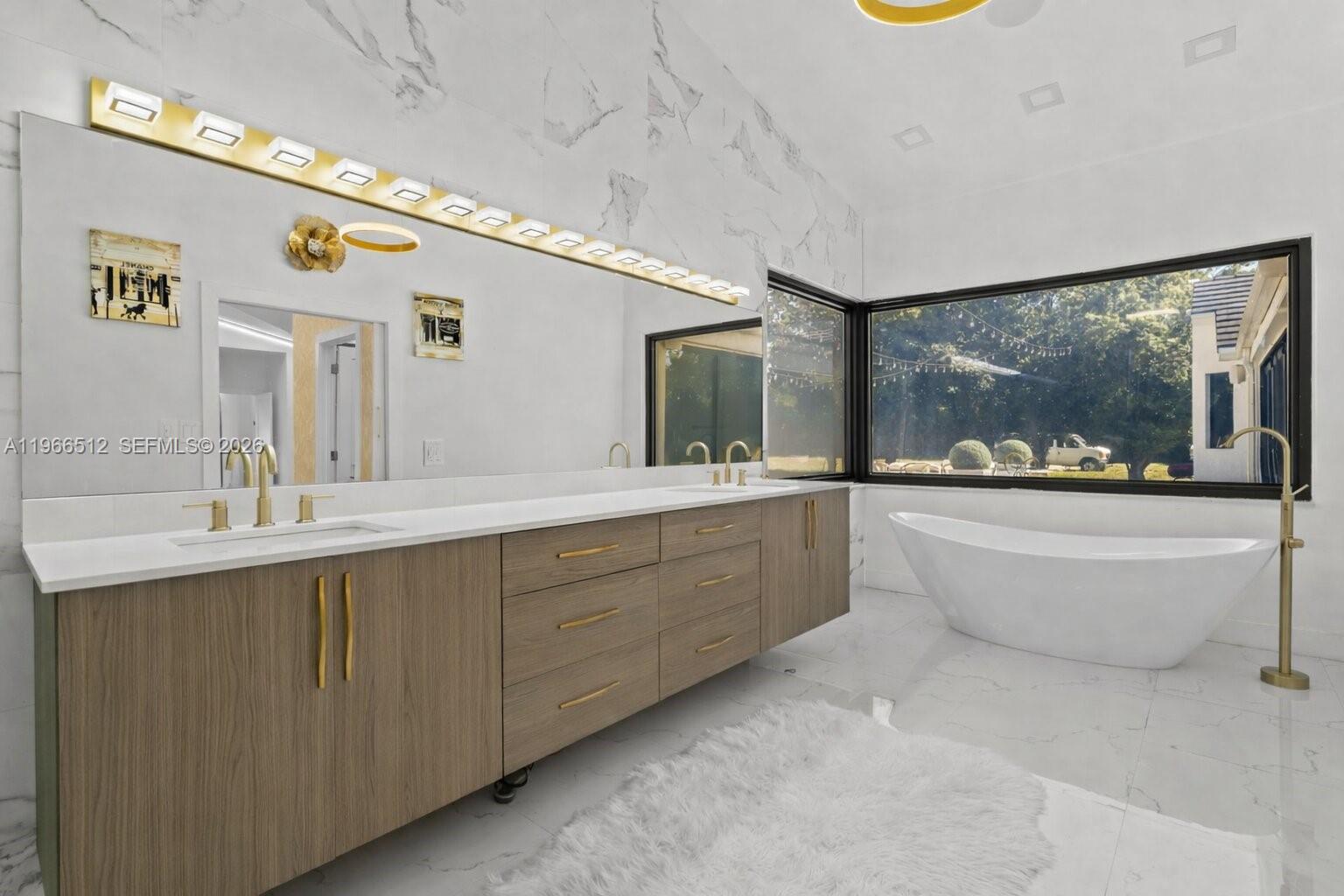 17795 Southwest 158th Street Miami, FL 33187 - Photo 15 of 31 a spacious bathroom with a double vanity sink a large mirror a bathtub and next to a window