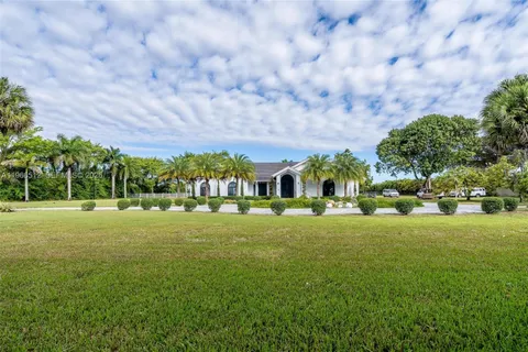 a view of a big house with a big yard and large trees