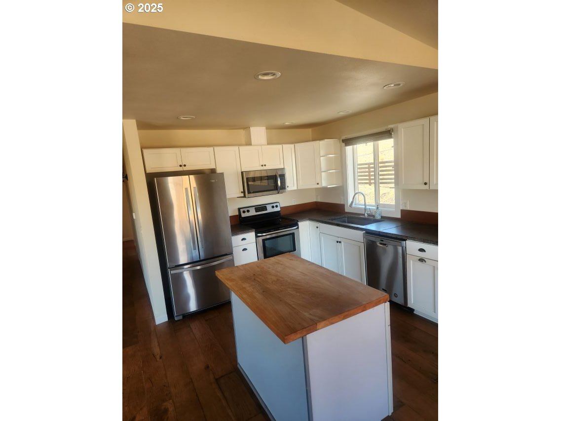 1335 Childers Road Arlington, OR 97812 - Photo 6 of 25 a kitchen with stainless steel appliances a kitchen island hardwood floor sink and stove