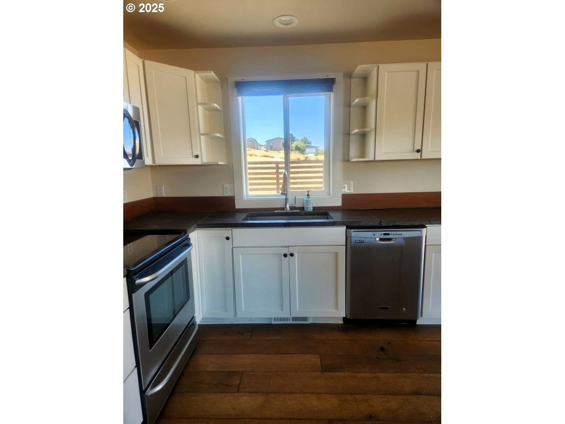 1335 Childers Road Arlington, OR 97812 - Photo 7 of 25 a kitchen with granite countertop white cabinets and black appliances