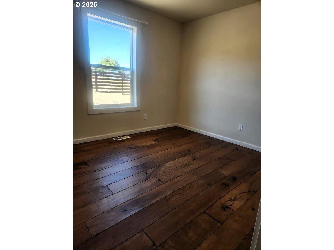 1335 Childers Road Arlington, OR 97812 - Photo 9 of 25 a view of an empty room with wooden floor and a window