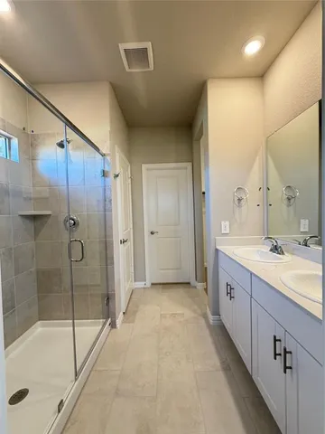a spacious bathroom with a shower a sink and a mirror