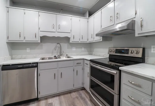 a kitchen with granite countertop white cabinets and stainless steel appliances