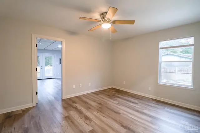 an empty room with wooden floor and windows