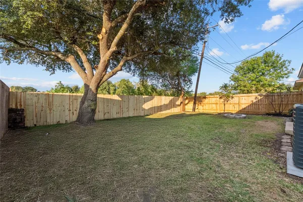 a view of backyard with tree and wooden fence