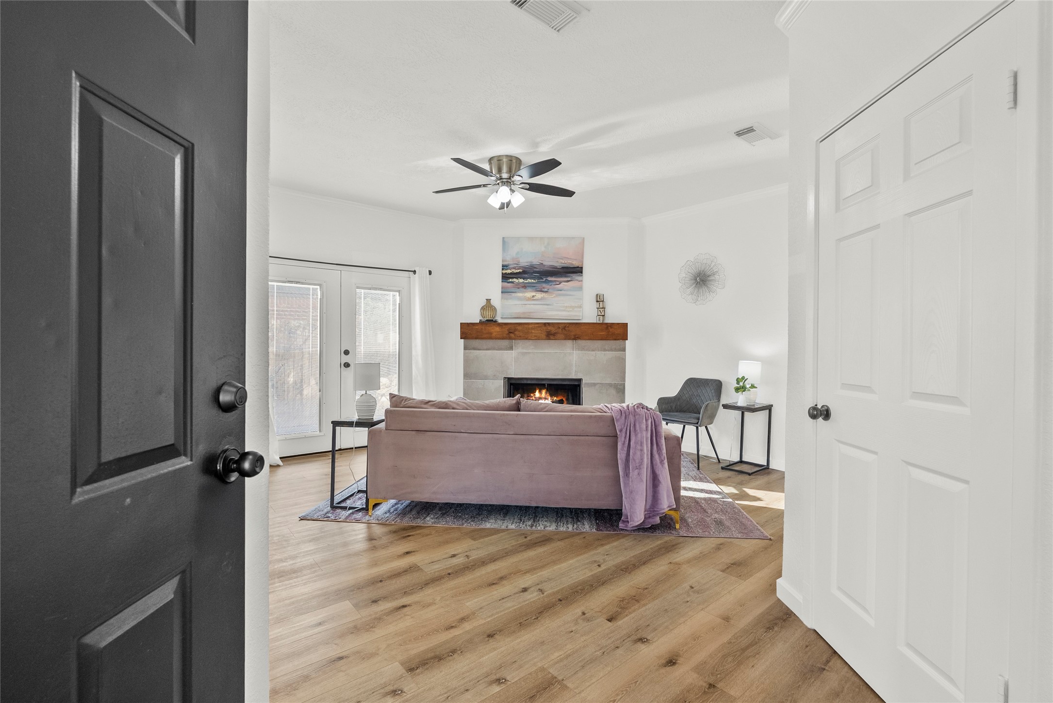617 Prairie Lane Angleton, TX 77515 - Photo 2 of 29 This cozy living room features a modern fireplace with a wooden mantel, comfortable seating area & large glass doors allowing natural light to flow in, creating a bright and inviting atmosphere.