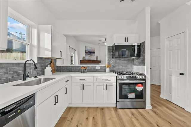 a kitchen with stainless steel appliances granite countertop a stove top oven a sink and dishwasher with wooden floors