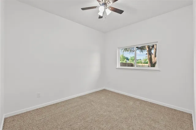 an empty room with a window and a chandelier fan