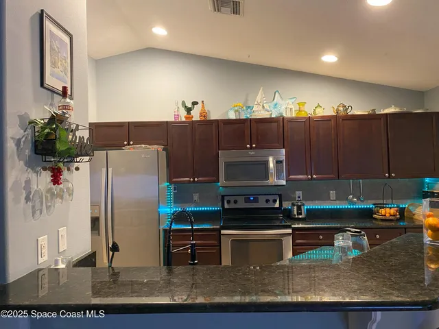 a kitchen with stainless steel appliances granite countertop a refrigerator a stove and a sink with wooden cabinets