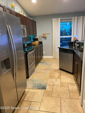 a kitchen with stainless steel appliances granite countertop a refrigerator a stove and a sink