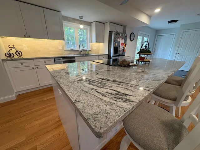 a view of a kitchen with kitchen island a counter top space a sink wooden floor and living room view