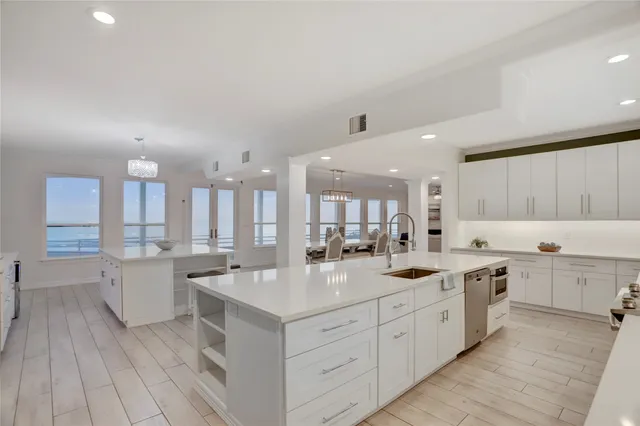 a large white kitchen with a sink and cabinets