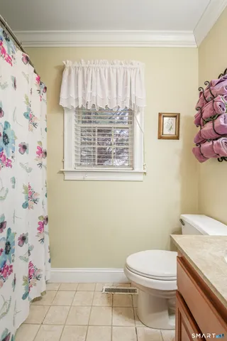 a bathroom with a granite countertop toilet a sink and a window