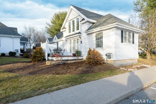 a view of a white house next to a yard
