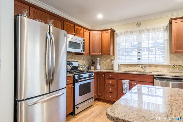 a kitchen with stainless steel appliances granite countertop a refrigerator a stove and a sink