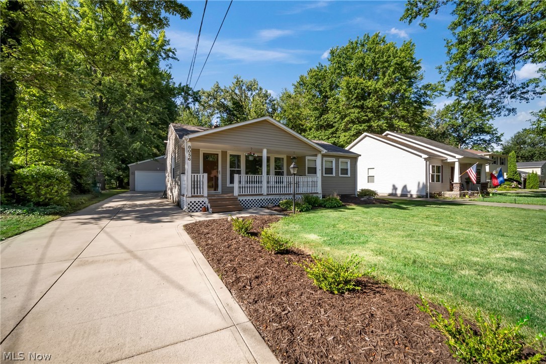 Ranch-style house featuring a porch, a garage, and a front yard