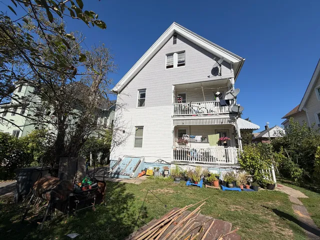 a view of a white house with a big yard and large trees