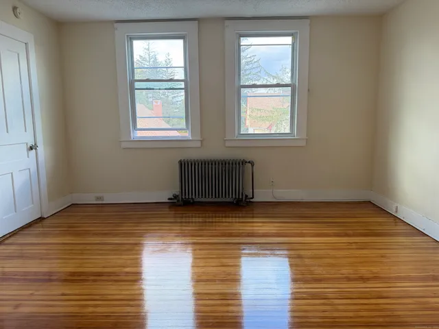 a view of empty room with wooden floor and window