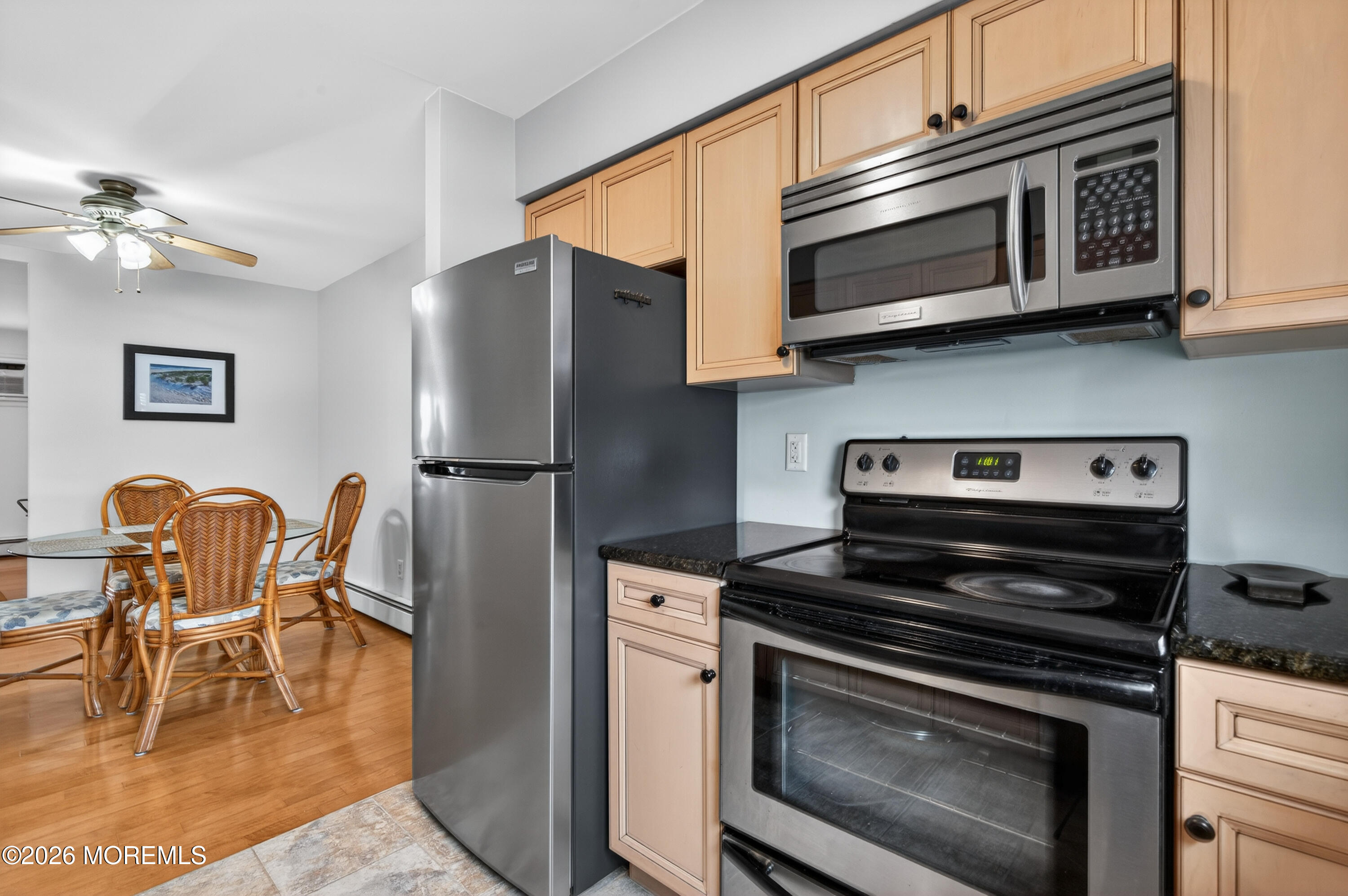 330 Highway 35, Unit 20 Point Pleasant Beach, NJ 08742 - Photo 12 of 22 a kitchen with stainless steel appliances granite countertop a stove top oven a refrigerator a dining table and chairs with wooden floors