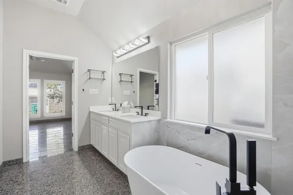 a bathroom with a tub sink and mirror
